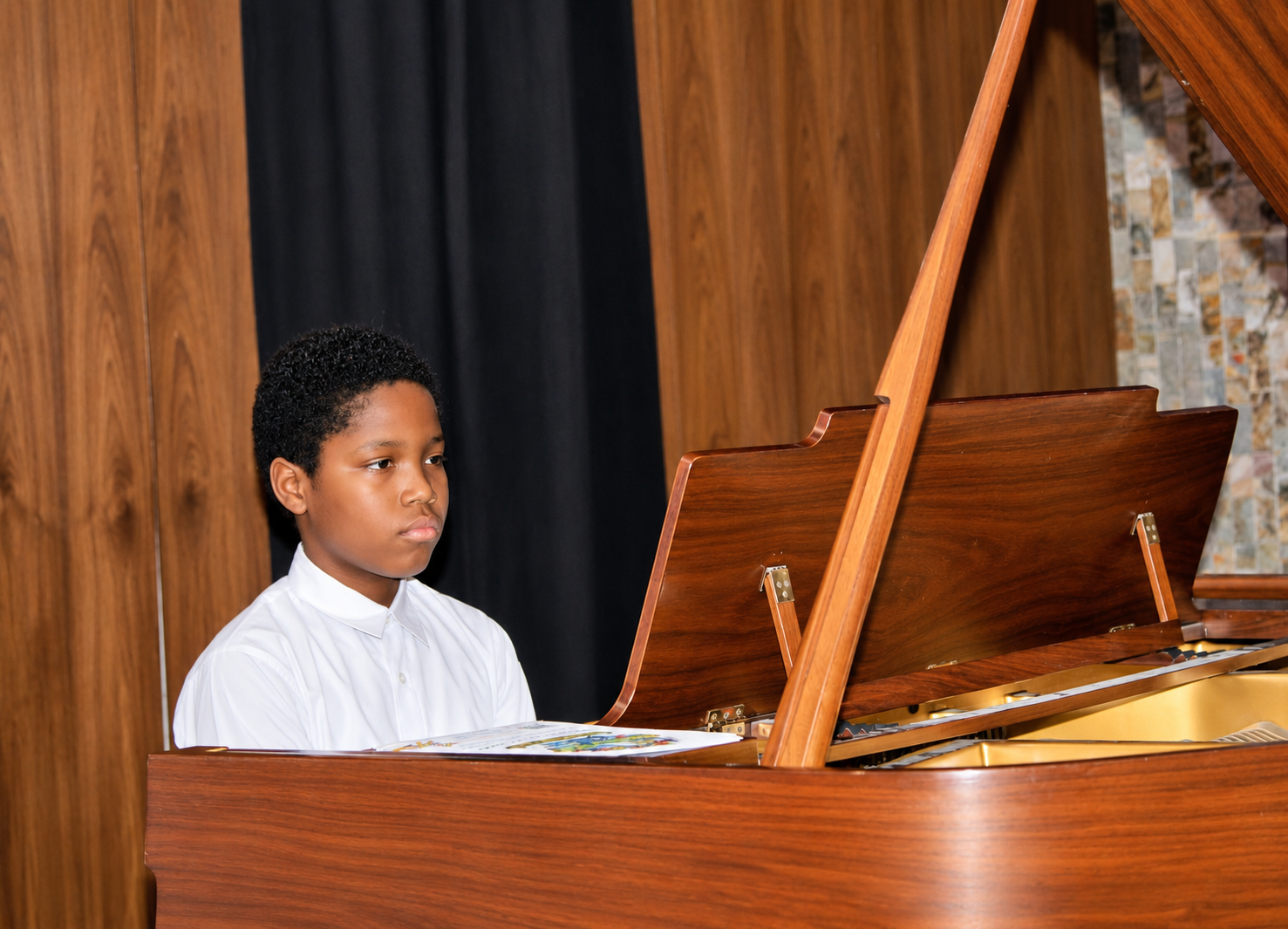 Student playing a grand piano during a Keys to Confidence beginner piano class